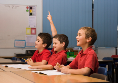 Primary age children answering questions and having fun in a classroom. Shallow focus is on the nearest boy. Adobe RGB 1998 profile.